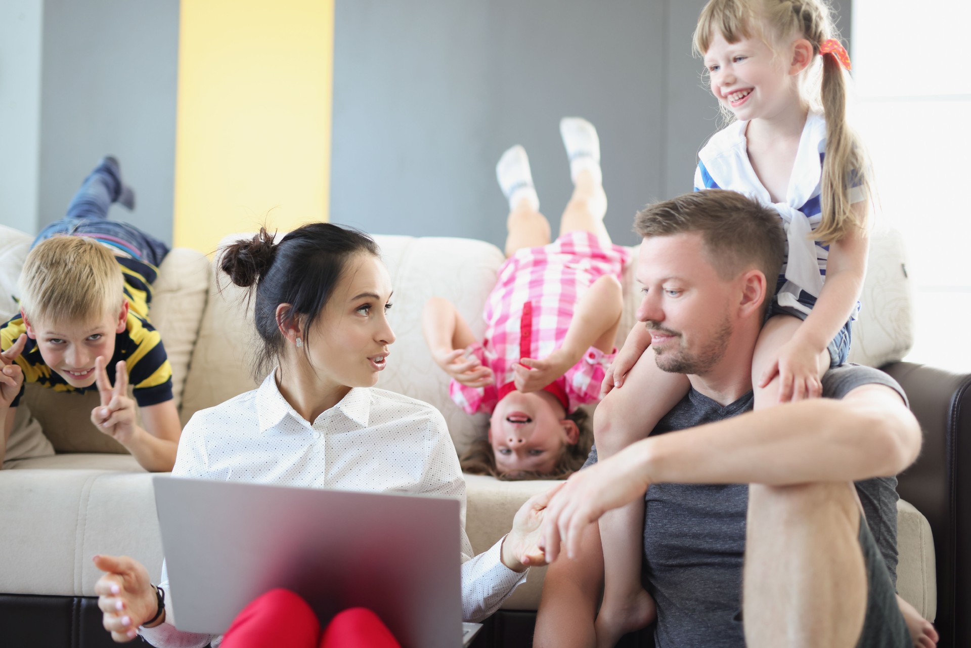 Mom and dad are talking to each other and children playing on laptop next to them
